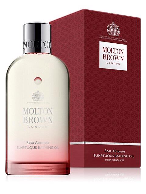 A bottle of MOLTON BROWN - ROSA ABSOLUTE BATH OIL stands before its matching red and white box, both displaying the MOLTON BROWN name and product branding.