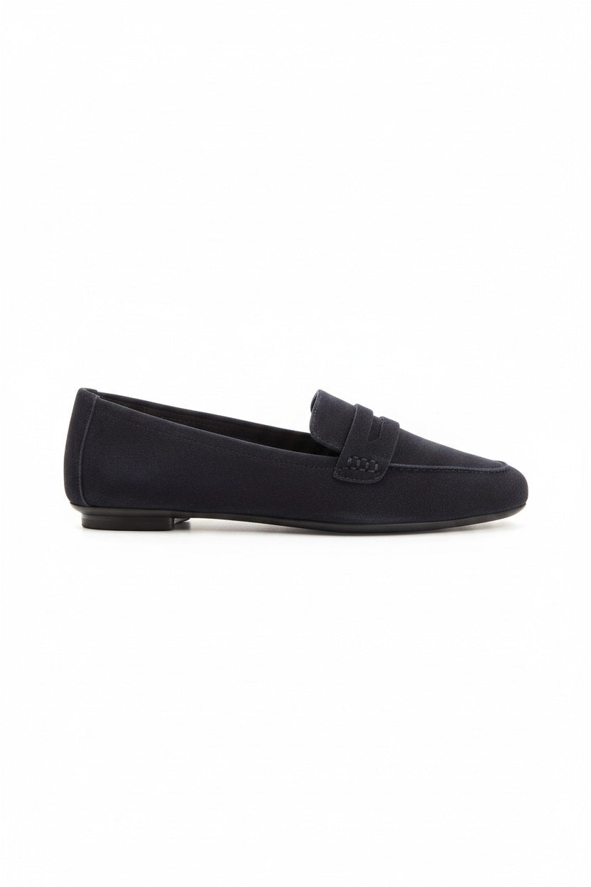 Six pairs of REQINS HEMA suede loafers in marine, featuring a classic penny loafer design and timeless silhouette, are displayed on a light tan surface in various blue and green shades.