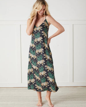A woman wearing the PRINTFRESH - BAGHEERA ECO SATIN CHIC TO SLEEP NIGHTIE IN INK by PRINTFRESH stands next to a women's size guide chart that demonstrates how to measure bust, waist, and hips. Her comfortable eco-friendly viscose nightie features the elegant Bagheera print. Sizes range from XXS to XL, with measurement details for bust, waist, and hips provided in inches.