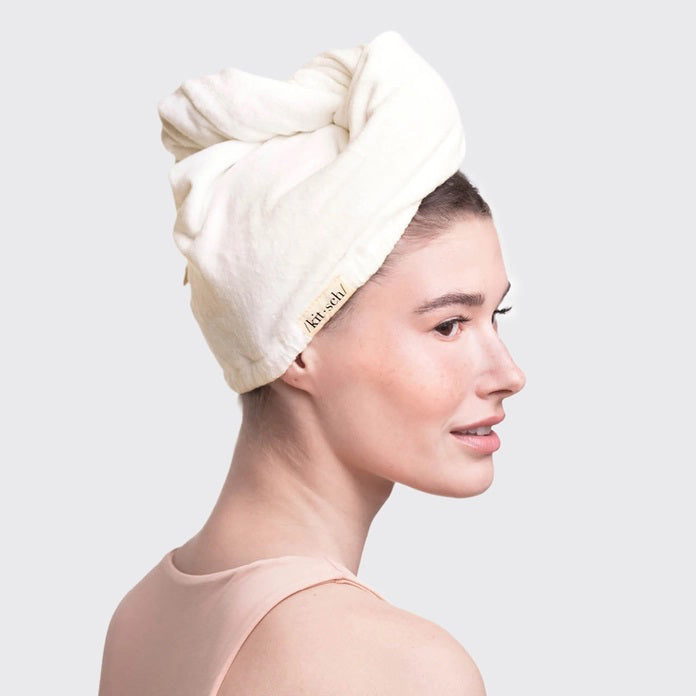 The KITSCH - QUICK DRY HAIR TOWEL, made from organic cotton and bamboo, features eco-friendly packaging with a teardrop design that promises frizz reduction for fine, curly, or straight hair. It includes an image of a person wearing the towel.