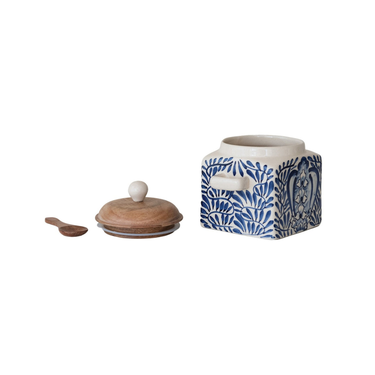 A close-up of the CREATIVE COOP HAND-PAINTED STONEWARE CANISTER WITH LID AND SPOON shows blue floral designs on cream stoneware and an acacia wood lid—an elegant farmhouse kitchen accent.