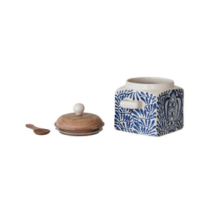 A close-up of the CREATIVE COOP HAND-PAINTED STONEWARE CANISTER WITH LID AND SPOON shows blue floral designs on cream stoneware and an acacia wood lid—an elegant farmhouse kitchen accent.
