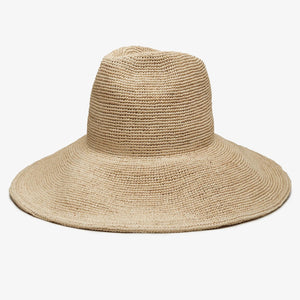 The WYETH HATS - LINA Raffia Sun Hat in Natural by WYETH features a packable, ultra wide brim and rounded crown, shown against a plain white background.