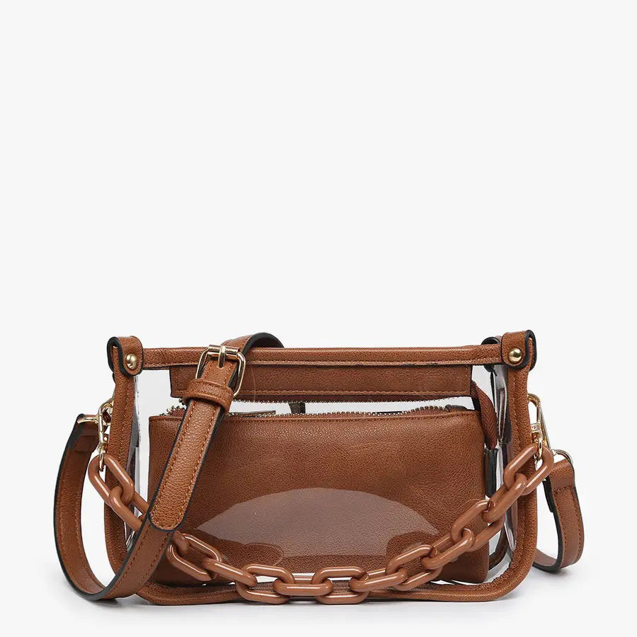 Introducing the CLEAR CROSSBODY BAG by JEN &amp; CO: A stylish handbag crafted from vegan leather, showcasing a layered beige design with an open top and a visible zipper pocket. This bag is elegantly framed by a transparent outer layer and is complemented by a chunky beige chain strap for additional style and versatility.