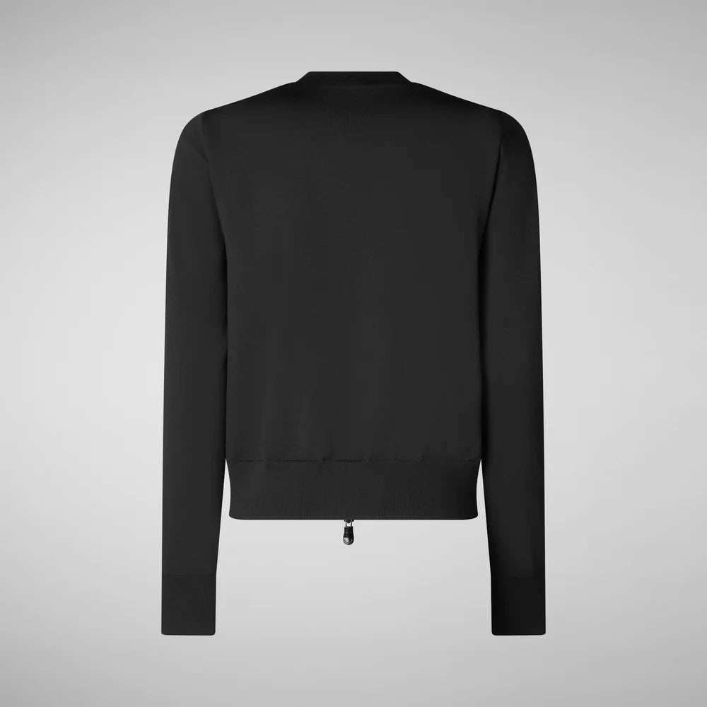 A person with medium-length hair stands against a plain background, wearing the SAVE THE DUCK - BRIONY PUFFER HYBRID JACKET and shorts for a cropped fit. White socks peek from their brown boots, hands in pockets, reflecting a neutral expression perfect for summer layering.