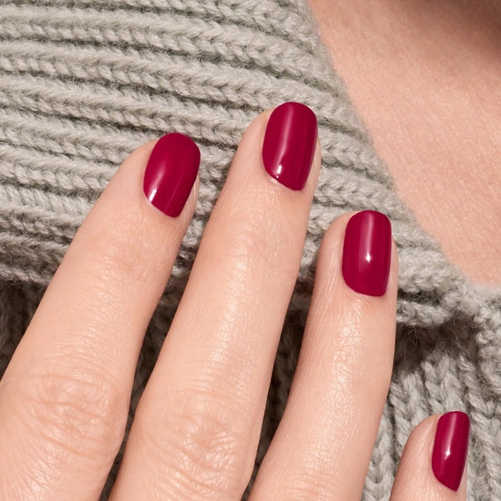 A bottle of MANUCURIST - GREEN™ Nail Polish in Violeta from MANUCURIST INC features a deep pinky purple shade, a black cap, and a label highlighting “green” and “quick dry intense color.”.