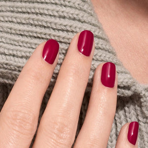 A bottle of MANUCURIST - GREEN™ Nail Polish in Violeta from MANUCURIST INC features a deep pinky purple shade, a black cap, and a label highlighting “green” and “quick dry intense color.”.
