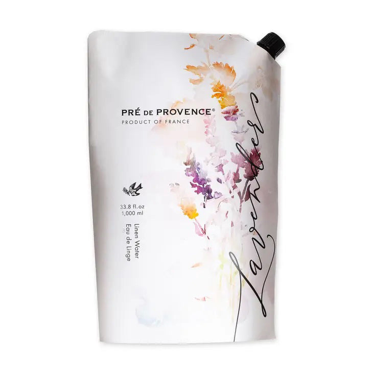A white stand-up pouch labeled &quot;Pré de Provence, Product of France&quot; with &quot;Lavender Linen Water Refill&quot; written in cursive on the right side. The pouch features a watercolor floral design in pastel colors and reads &quot;33.8 fl oz, 1000 ml&quot; on the front, promising a calming fragrance for use with your steam iron. The product is by European Soaps, LLC.
