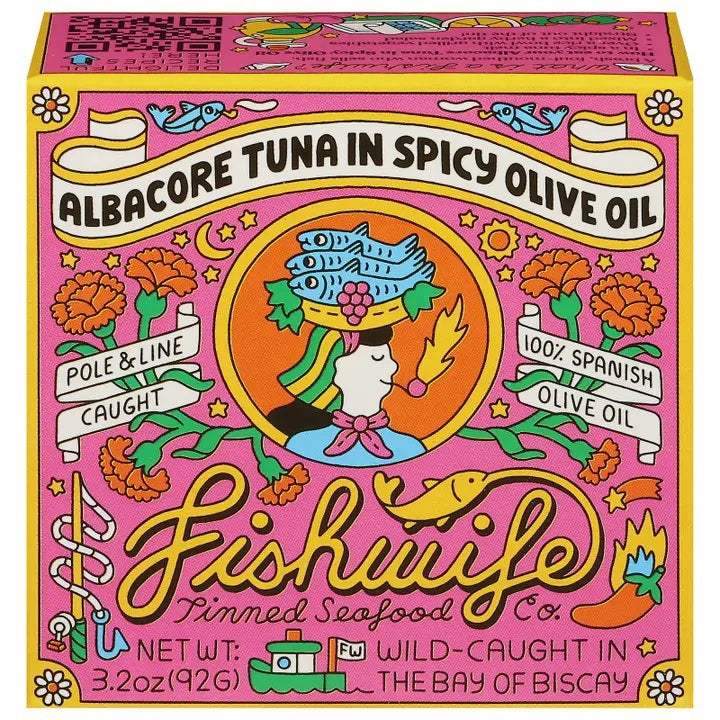 An open can of FISHWIFE - WILD CAUGHT SPICY ALBACORE TUNA, showing large, light brown pieces packed in oil or sauce, against a plain white background.