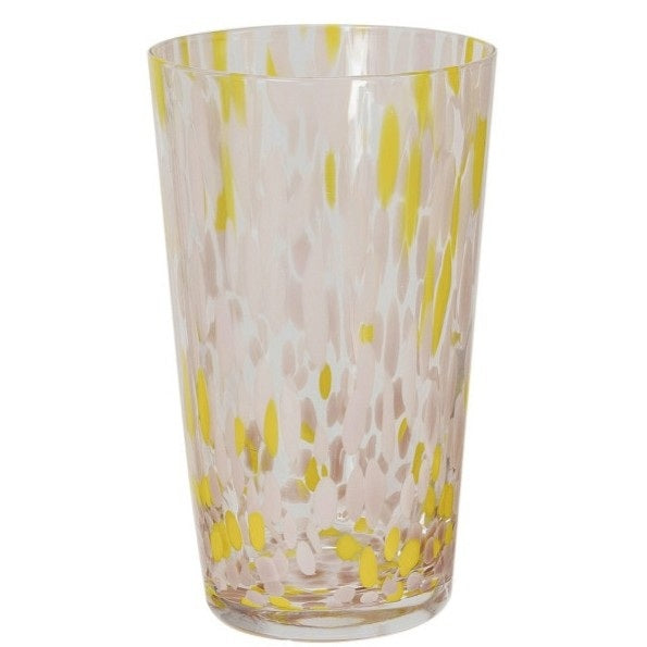 A selection of CREATIVE COOP HAND-BLOWN CONFETTI DRINKING GLASS tumblers, each with red, yellow, and pastel speckles, is displayed on a light surface; a tall glass holds drink stirrers and a cocktail recipe card.