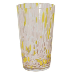 A selection of CREATIVE COOP HAND-BLOWN CONFETTI DRINKING GLASS tumblers, each with red, yellow, and pastel speckles, is displayed on a light surface; a tall glass holds drink stirrers and a cocktail recipe card.