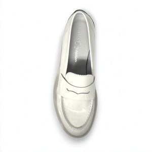 A single ANNA Loafer in Butter by MICHELE LOPRIORE, made with beige patent leather and featuring a chunky rubber sole, is displayed against a white background. This classic shoe showcases subtle stitched details and boasts a 3 cm height for added style.