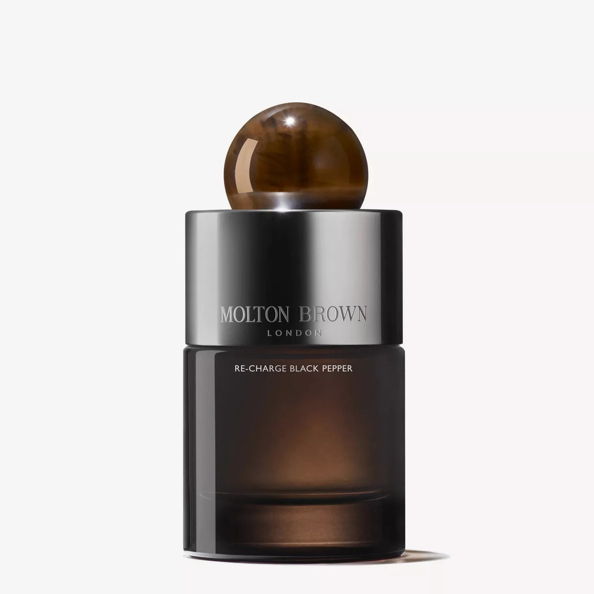 A 100ml bottle of MOLTON BROWN - RE-CHARGE BLACK PEPPER EAU DE PARFUM, with a sleek dark glass and marbled brown cap, stands against a white background—an adventurous scent from MOLTON BROWN for the bold.