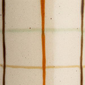 Close-up of the HAND-PAINTED STONEWARE PITCHER by CREATIVE COOP, showcasing an artisanal beige surface with a grid of brown, orange, and light green, plus small dark speckles for added charm.