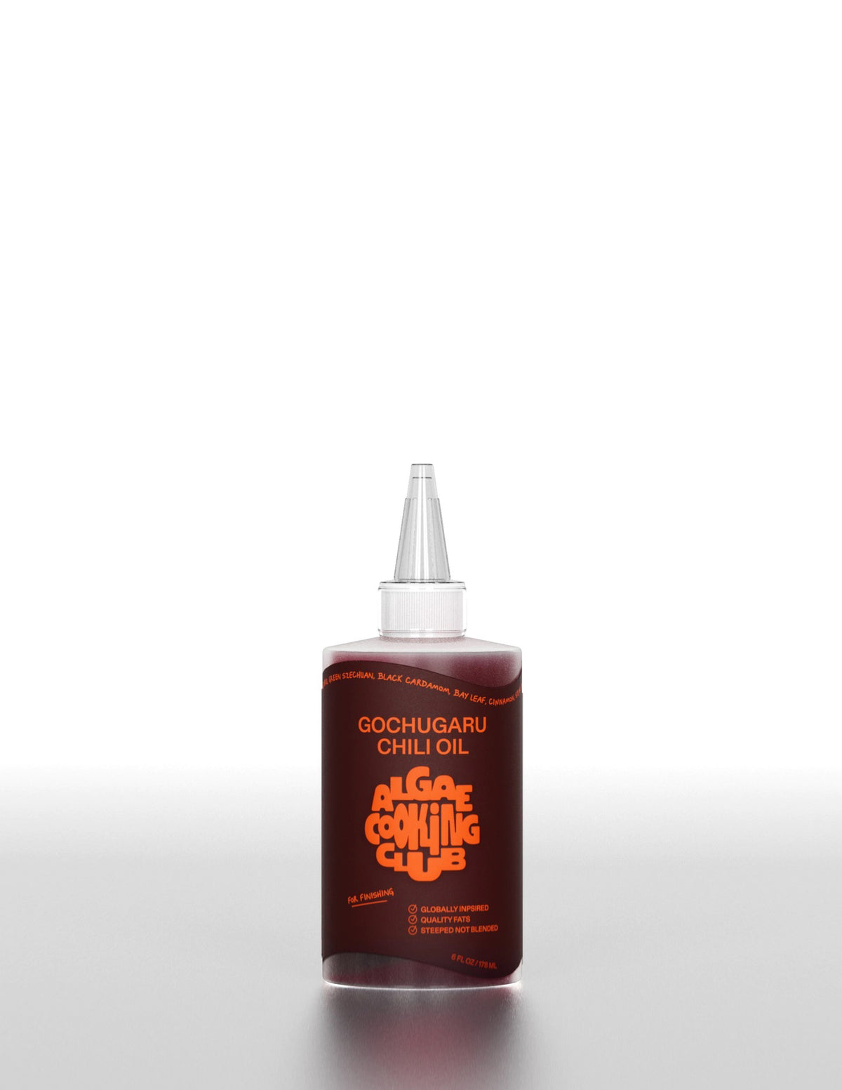 A clear plastic bottle labeled &quot;ALGAE COOKING CLUB - GOCHUGARU CHILI OIL&quot; in bold orange text sits on a white surface against a plain background, holding vibrant Korean chili oil from ALGAE COOKING CLUB.
