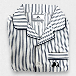 The PETITE PLUME FEARRINGTON LIFESTYLE COLLECTION - CHILDREN'S TWILL NAVY FRENCH TICKING PAJAMA SET is a delightful option for kids, featuring long sleeves and pants with chic vertical white and gray stripes. This set is crafted from yarn-dyed cotton, boasting a top with a collar, full button-down front, and a single chest pocket adorned with matching fabric piping along the cuffs and pocket opening.