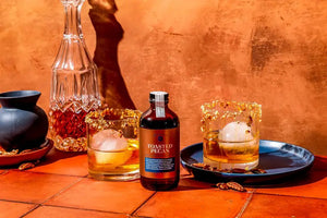 A brown glass bottle labeled "YES COCKTAIL CO - TOASTED PECAN SYRUP" features a handwritten-style signature and decorative elements. It describes caramel and buttery flavors, perfect for an old fashioned cocktail. Bottle size: 8 fl oz (237 mL). Brand: YES COCKTAIL CO.