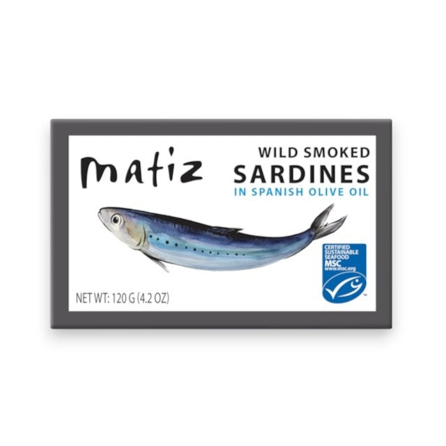 A blue-edged box of MATIZ ESPANA Wild Caught Smoked Sardines in Organic Olive Oil showcases an illustrated sardine, product info, and nutrition highlights. These wild-caught, bone-in sardines have a net weight of 120g (4.2 oz).
