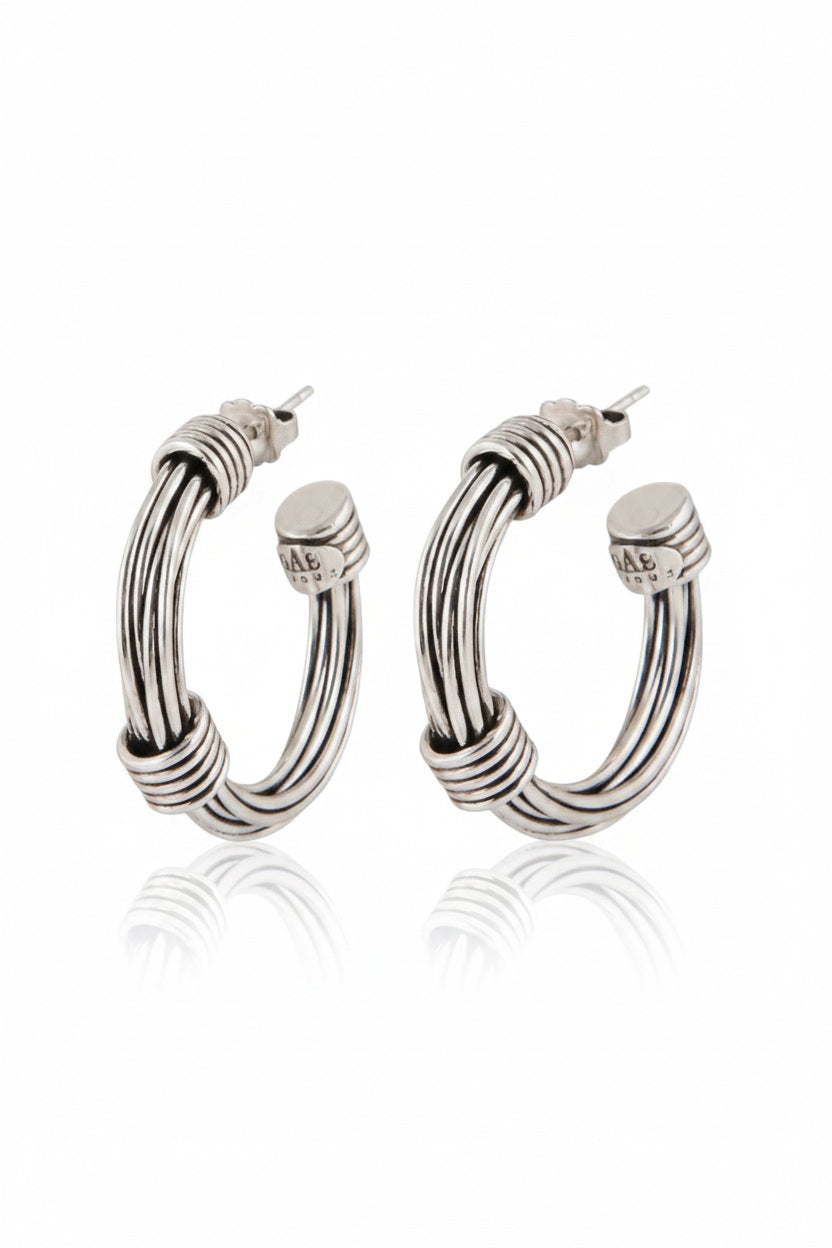 The GAS BIJOUX ARIANE SILVER HOOP EARRINGS are a stylish pair of silver hoops with a diameter of 2.7 cm, boasting a sleek and polished design accented by wrapped metallic threads at both the top and bottom. The reflective finish on the studs adds an elegant touch.