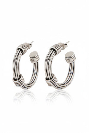 The GAS BIJOUX ARIANE SILVER HOOP EARRINGS are a stylish pair of silver hoops with a diameter of 2.7 cm, boasting a sleek and polished design accented by wrapped metallic threads at both the top and bottom. The reflective finish on the studs adds an elegant touch.