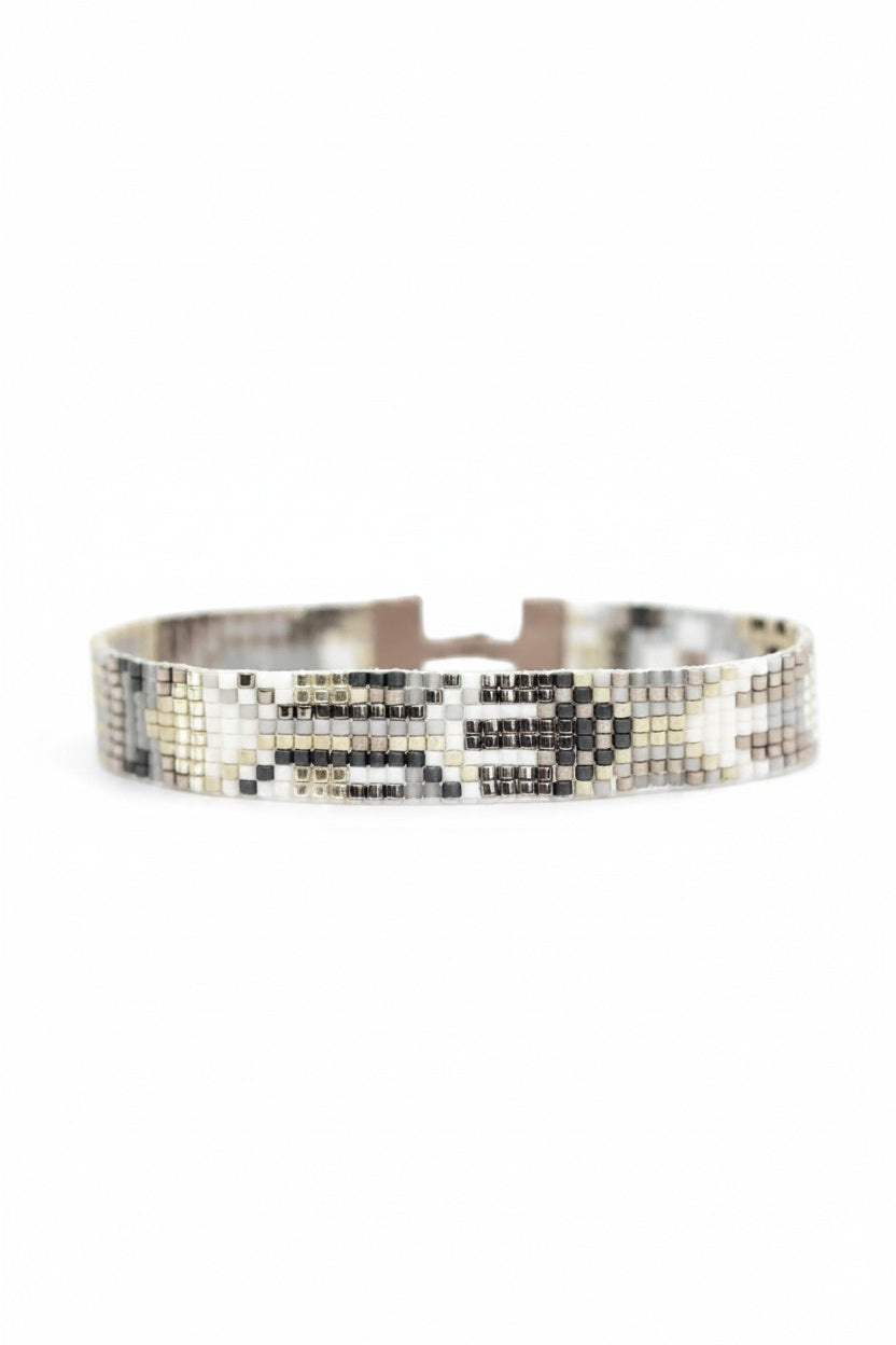 Introducing the JULIE ROFMAN - OSLO BRACELET by JULIE ROFMAN JEWELRY: A beaded bracelet that boasts a captivating geometric design in beige, gray, and brown hues. It features a stylish leather strap with a metallic clasp at the centerpiece and an adjustable closure to ensure the perfect fit.