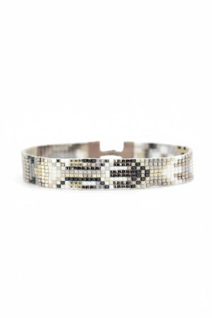 Introducing the JULIE ROFMAN - OSLO BRACELET by JULIE ROFMAN JEWELRY: A beaded bracelet that boasts a captivating geometric design in beige, gray, and brown hues. It features a stylish leather strap with a metallic clasp at the centerpiece and an adjustable closure to ensure the perfect fit.