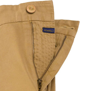 Close-up of PENNBILT - THE PLAINSMAN PANT IN DARK KHAKI, featuring tan Pima cotton fabric with a partially unzipped brass zipper and an open button. A blue “PENNBILT” label is sewn near the waistband.