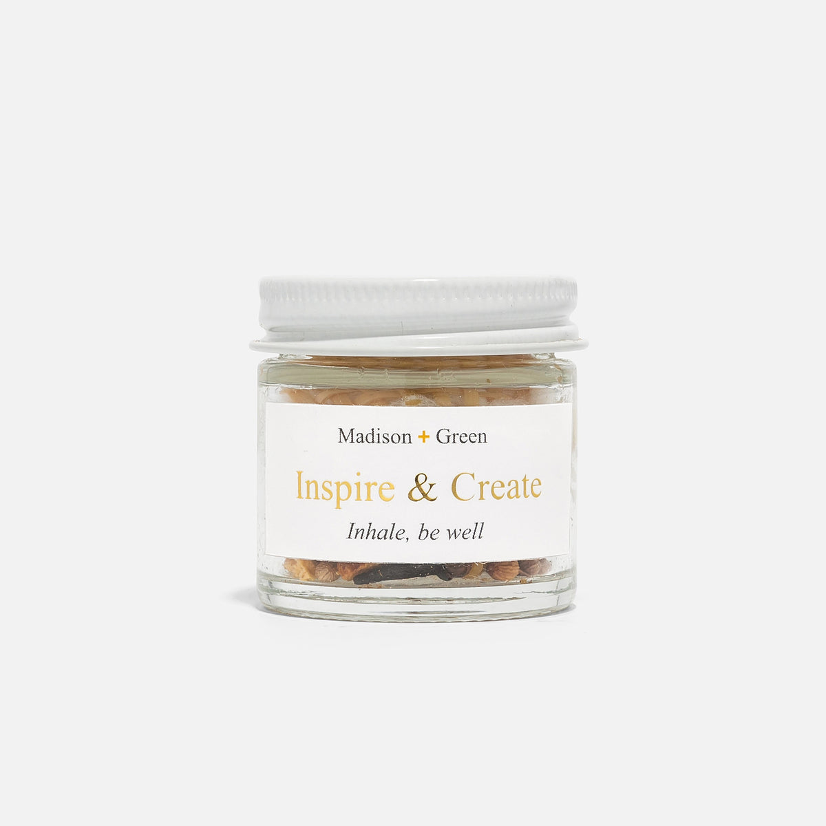 A small glass jar holds granola and yogurt, topped with a woven piece. Next to it, the MADISON GREEN INSPIRE AND CREATE Creativity Boost Aromatherapy Inhaler rests by the lid on a white surface, inviting inspiration.