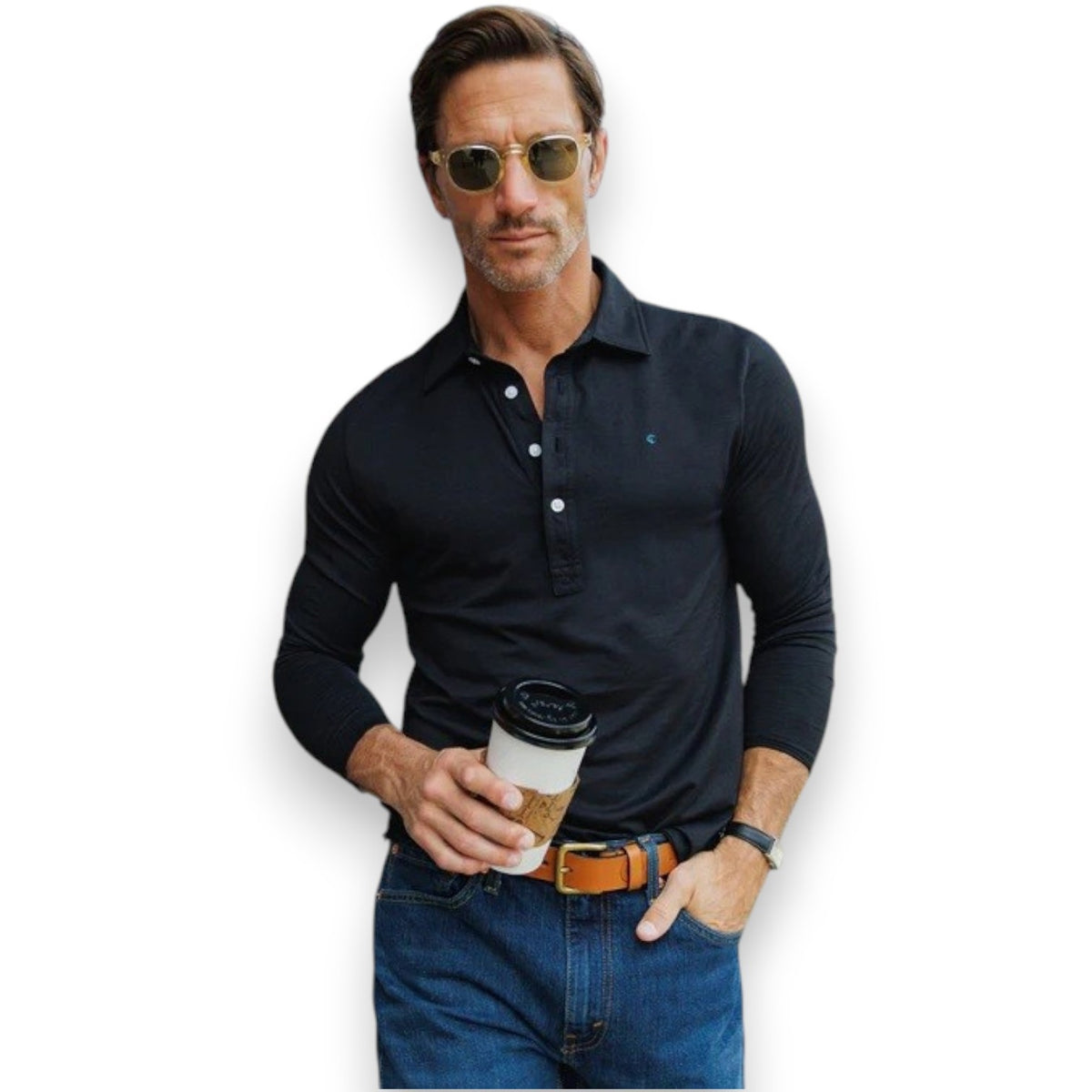 A man with short brown hair, wearing sunglasses, blue jeans, and the CRIQUET BRRR° Long Sleeve Range Polo in Dark Knight by CRIQUET, holds a takeaway coffee cup while standing against a white background.