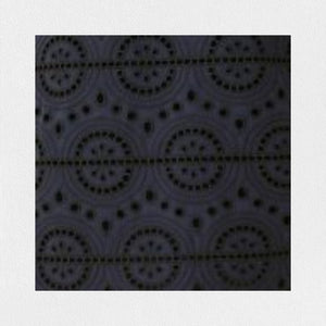 A person stands against a plain background wearing the SFIZIO - BRODERIE ANGLAISE MIDI DRESS by SFIZIO, which features elbow-length puffed sleeves and a midi-length skirt adorned with intricate lace patterns. They are also wearing black ankle-strap sandals.