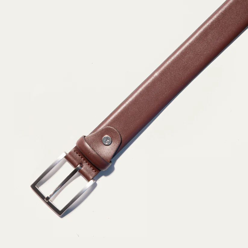 The WILL LEATHER GOODS Glazed Calfskin Belt in Cognac features a silver rectangular buckle and is shown diagonally on a plain white background.