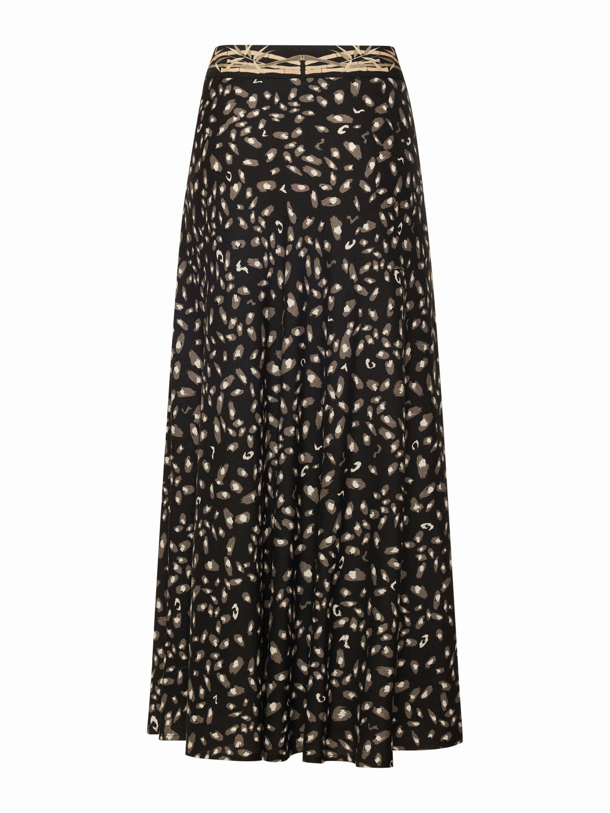 A person stands on a concrete floor wearing the FRANCO FERRARI - JEMMA WOOL MIDI SKIRT, a dark patterned jacket over their shoulders, a sheer patterned top, and black-and-white shoes. Their face is partially out of frame.