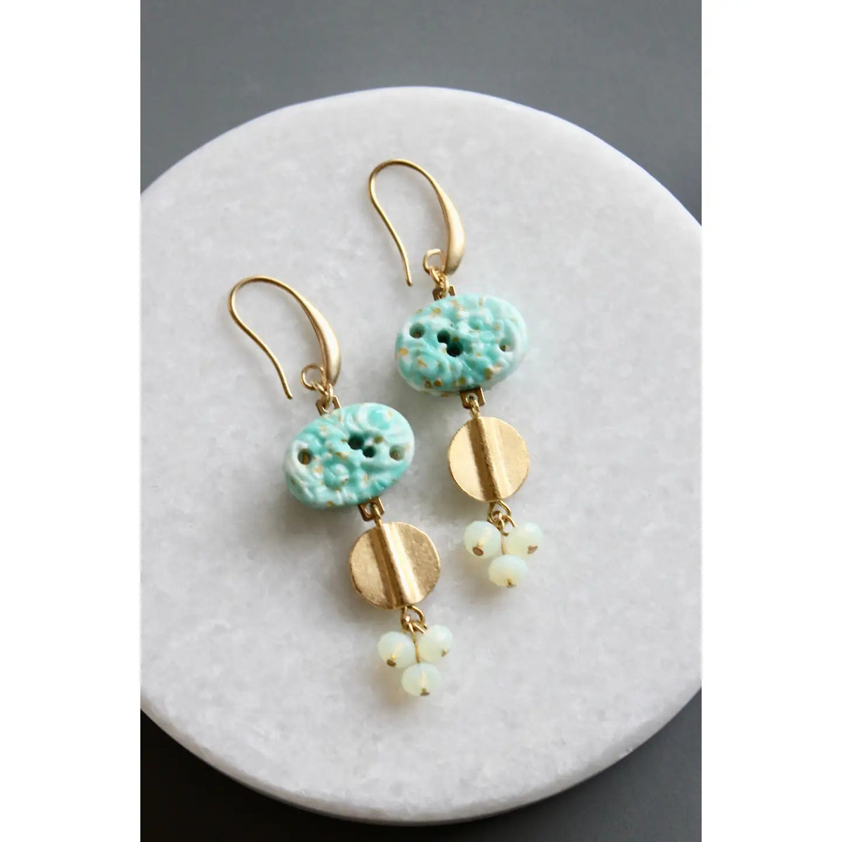 The DAVID AUBREY - VINTAGE TURQUOISE GLASS CLUSTER EARRINGS by DAVID AUBREY feature gold plated ear wires, turquoise glass beads, round gold accents, and delicate clusters of small white beads, beautifully displayed on a round white surface.