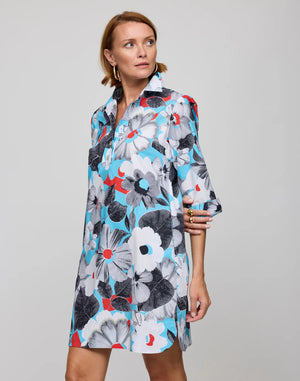 The person is wearing the HINSON WU Aileen dress, featuring a knee-length cut in stretch polished cotton with a pop art flower print in blue, black, white, and red. It has a collared neckline and three-quarter sleeves, stylishly set against a plain gray background.