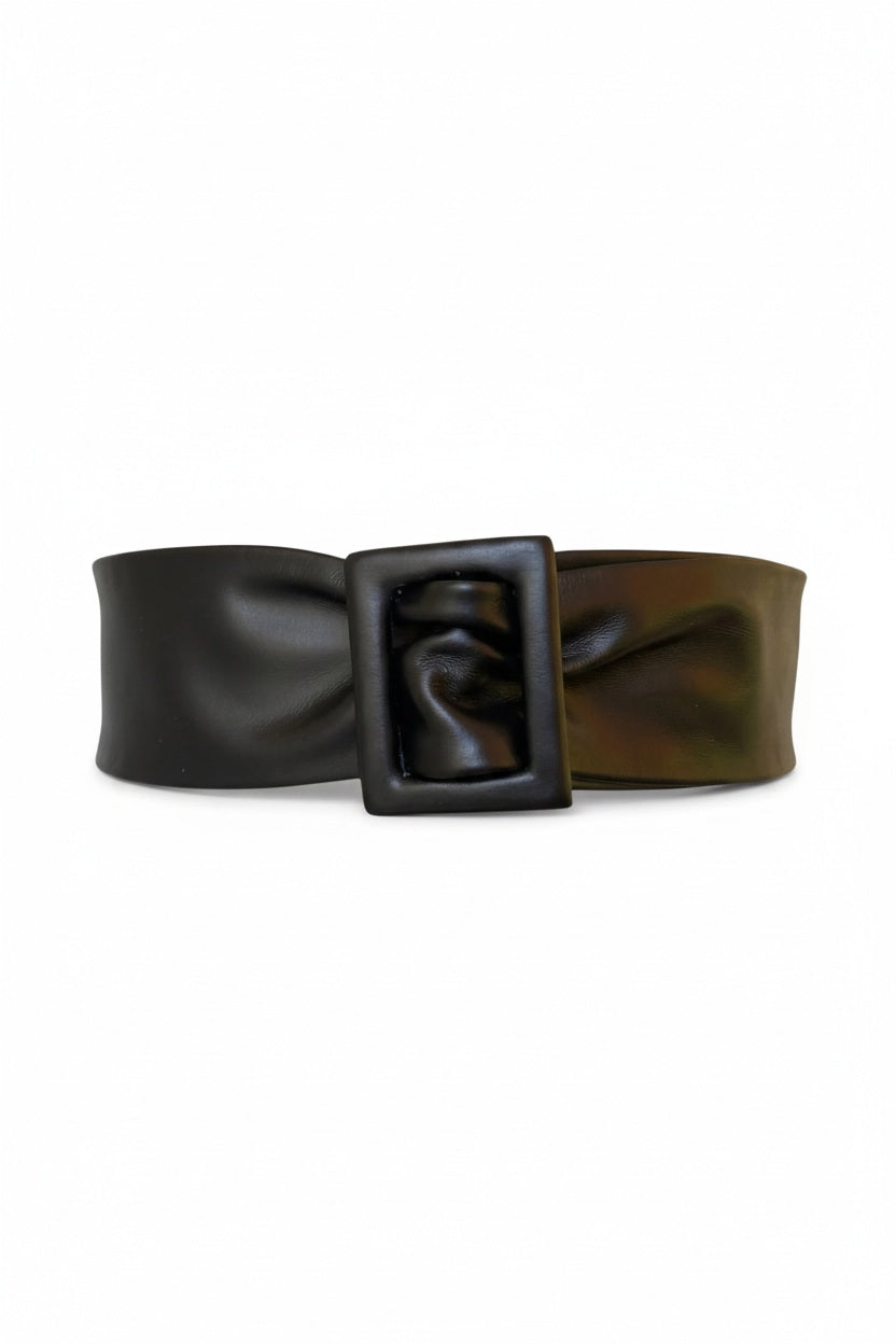 The APROPOS BELT by ADA is a handcrafted brown leather belt with a wide band and smooth texture. Made from genuine Argentinian leather, it features a rectangular buckle, showcased on a plain white background.