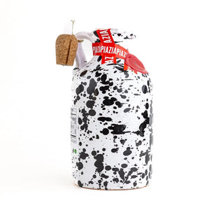 Introducing the GALANTINO - LEMON EXTRA VIRGIN OLIVE OIL from ZIA PIA IMPORTS: a hand-painted ceramic bottle with a cork, featuring a white finish adorned with black splatter patterns and red accents. Standing upright on a white background, it’s perfect for presenting your favorite flavored olive oil.
