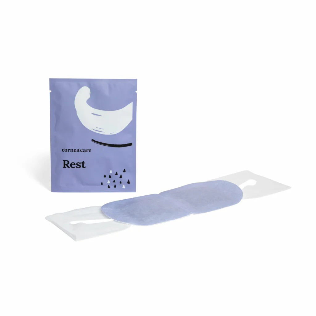 Hands hold a CORNEACARE - REST Self Heating Warm Compress as one hand removes a gray eye patch. The light blue pouch&#39;s minimalist design highlights its soothing eye dryness relief, enhanced by black and white elements on a plain backdrop.