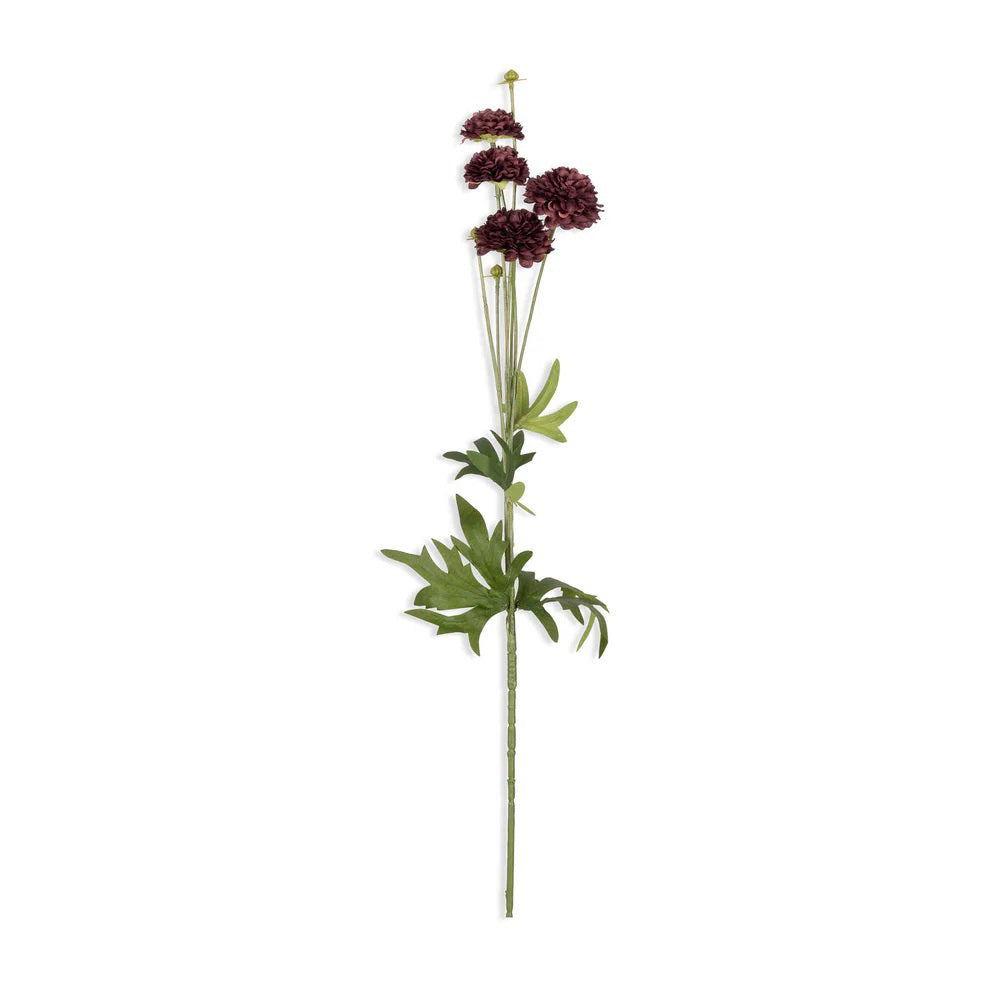 Several ABIGAIL AHERN - CLOVE STEM faux flowers with green stems and deep burgundy hues are arranged on a textured gray surface, accompanied by a pair of black scissors and a rustic bowl.