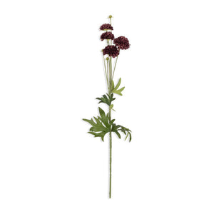 Several ABIGAIL AHERN - CLOVE STEM faux flowers with green stems and deep burgundy hues are arranged on a textured gray surface, accompanied by a pair of black scissors and a rustic bowl.