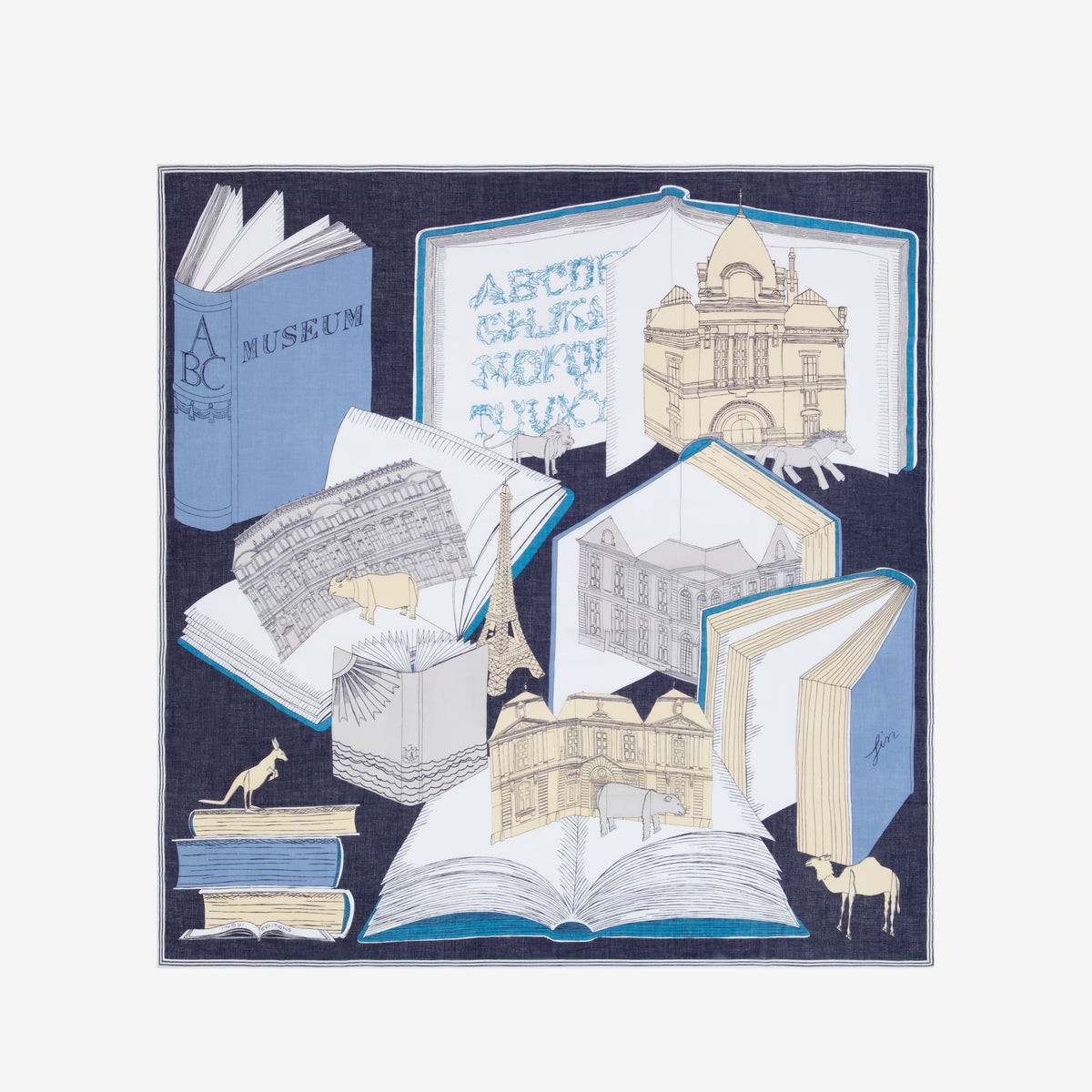 The INOUI EDITIONS - MUSEUM SCARF IN NAVY by INOUI features open books with architectural sketches—buildings, arches, the Eiffel Tower—on a navy background, with small giraffe figures among the books and stacked volumes.