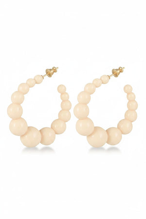 The GAS BIJOUX - CREOLE ANDY EARRINGS are a pair of hoop earrings designed with graduated cream-colored beads that mimic delicate acetate pearls, arranged from smaller at the top to larger toward the bottom. These sophisticated earrings come with a gold-tone post and backing, blending classic charm with a modern flair.