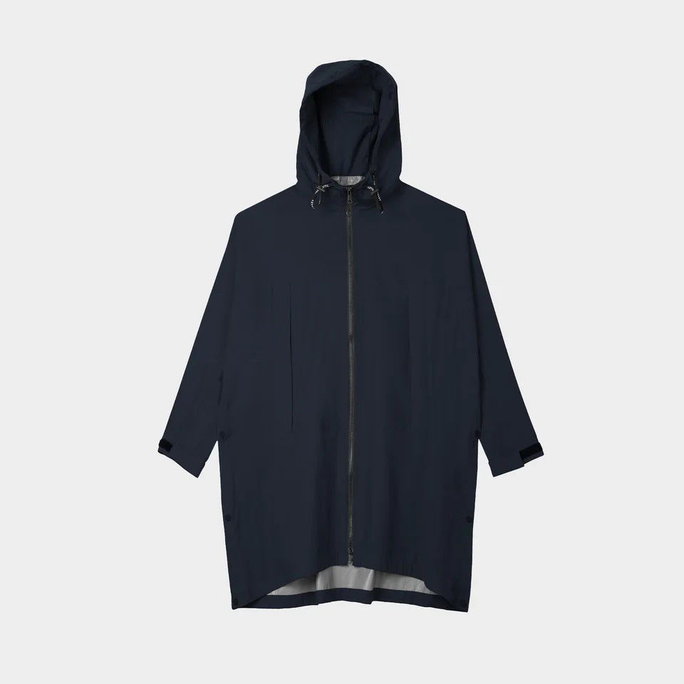 A person with short, wavy hair is seen from behind wearing the TILLEY - PACKABLE HOODED PONCHO by TILLEY in dark navy, featuring a hood and a loose, water-repellent fit, set against a plain light background.