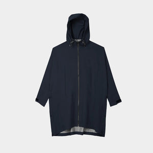 A person with short, wavy hair is seen from behind wearing the TILLEY - PACKABLE HOODED PONCHO by TILLEY in dark navy, featuring a hood and a loose, water-repellent fit, set against a plain light background.