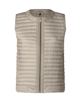 A woman with short brown hair wears the SAVE THE DUCK MARA PUFFER VEST over a white t-shirt and beige pants, standing against a plain light background and looking at the camera with a neutral expression.