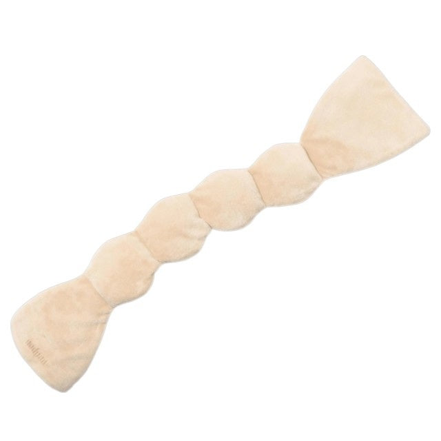 The NODPOD Weighted Sleep Eye Mask in Bone by NODPOD is a beige, segmented, plush mask with wider ends and a gently wavy, narrower middle section, shown laid flat on a white background—ideal for providing gentle pressure and soothing comfort as a weighted eye mask.