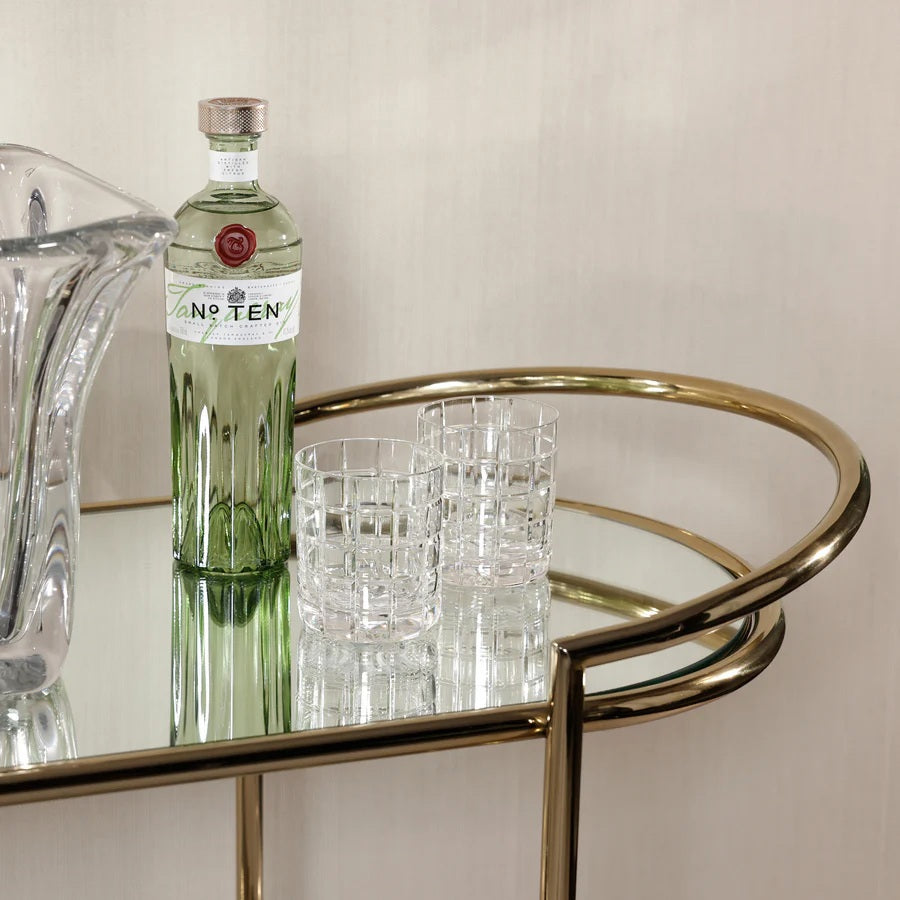 The ZODAX CONSOLE BAR CART showcases a minimalistic design with a shiny gold metal frame, mirrored shelves, curved corners, and clean lines—making it a stylish serving station for any modern space.