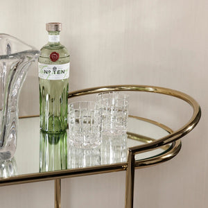The ZODAX CONSOLE BAR CART showcases a minimalistic design with a shiny gold metal frame, mirrored shelves, curved corners, and clean lines—making it a stylish serving station for any modern space.