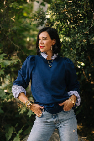 A person with long hair embraces comfort and individuality, wearing a KMJ SHIRTS Cooper Sweatshirt in gray with a white bow. Metallic sequin pants and silver shoes complete the look as they stand among disco balls on the floor against a plain background.
