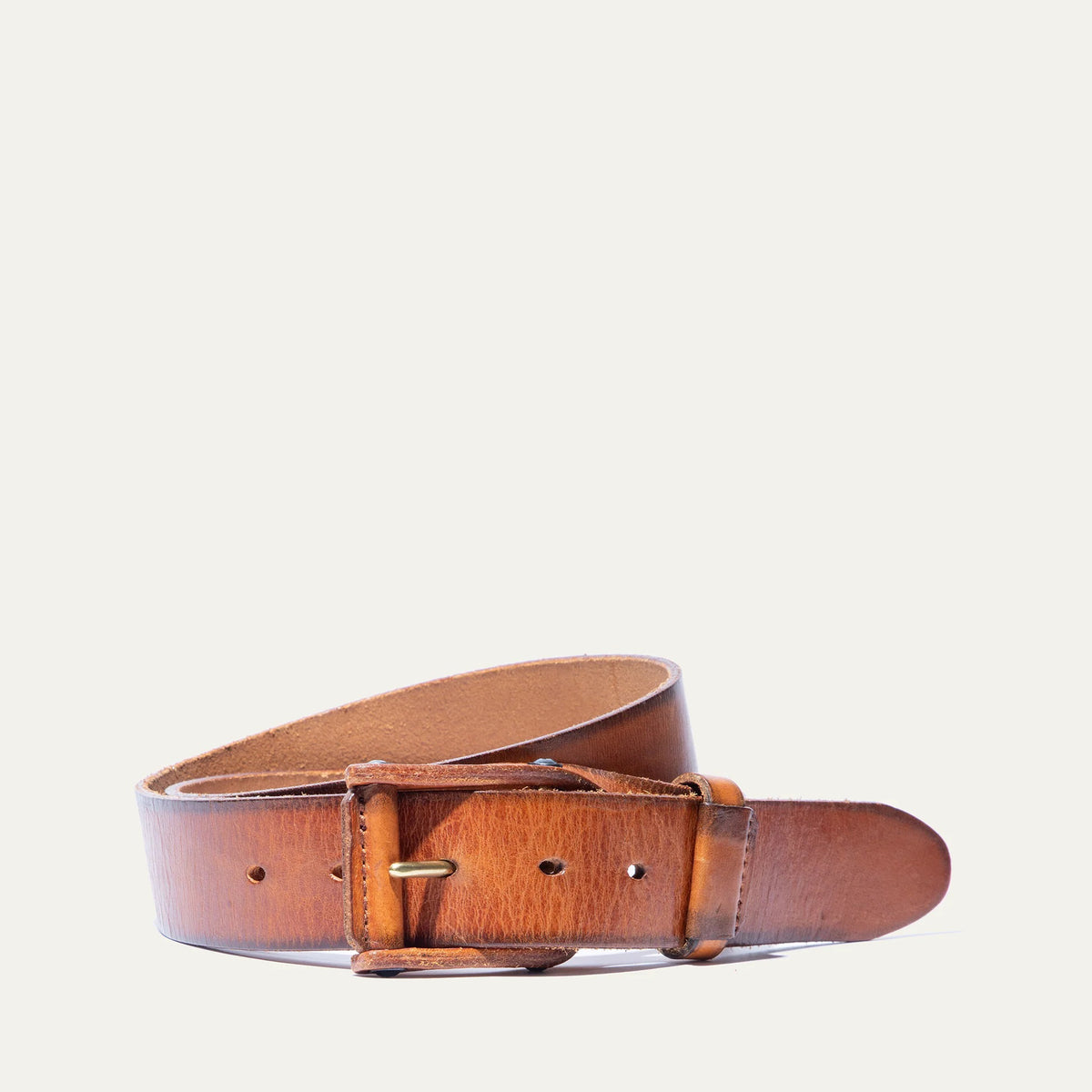 A close-up of the WILL LEATHER GOODS - LEATHER BUCKLE BELT by WILL LEATHER GOODS, featuring brown full-grain leather with a natural texture and slightly worn look, plus a gold metal buckle, displayed diagonally on a white background.