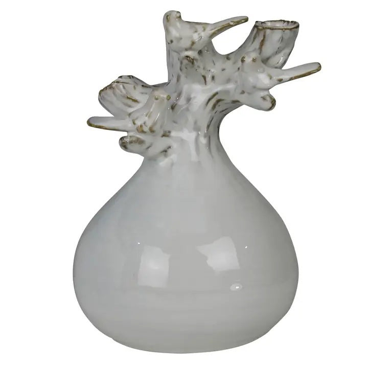 The HOMART CERAMIC VASE WITH BRANCH AND BIRD features white flowers and branches, set on a wooden surface with framed bird art and a woven basket against a light gray textured wall for a cozy touch.